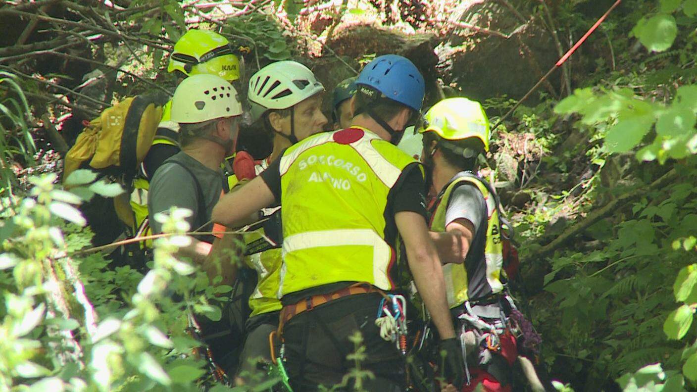 Gli uomini del soccorso alpino trasportano i feriti nel fitto del bosco