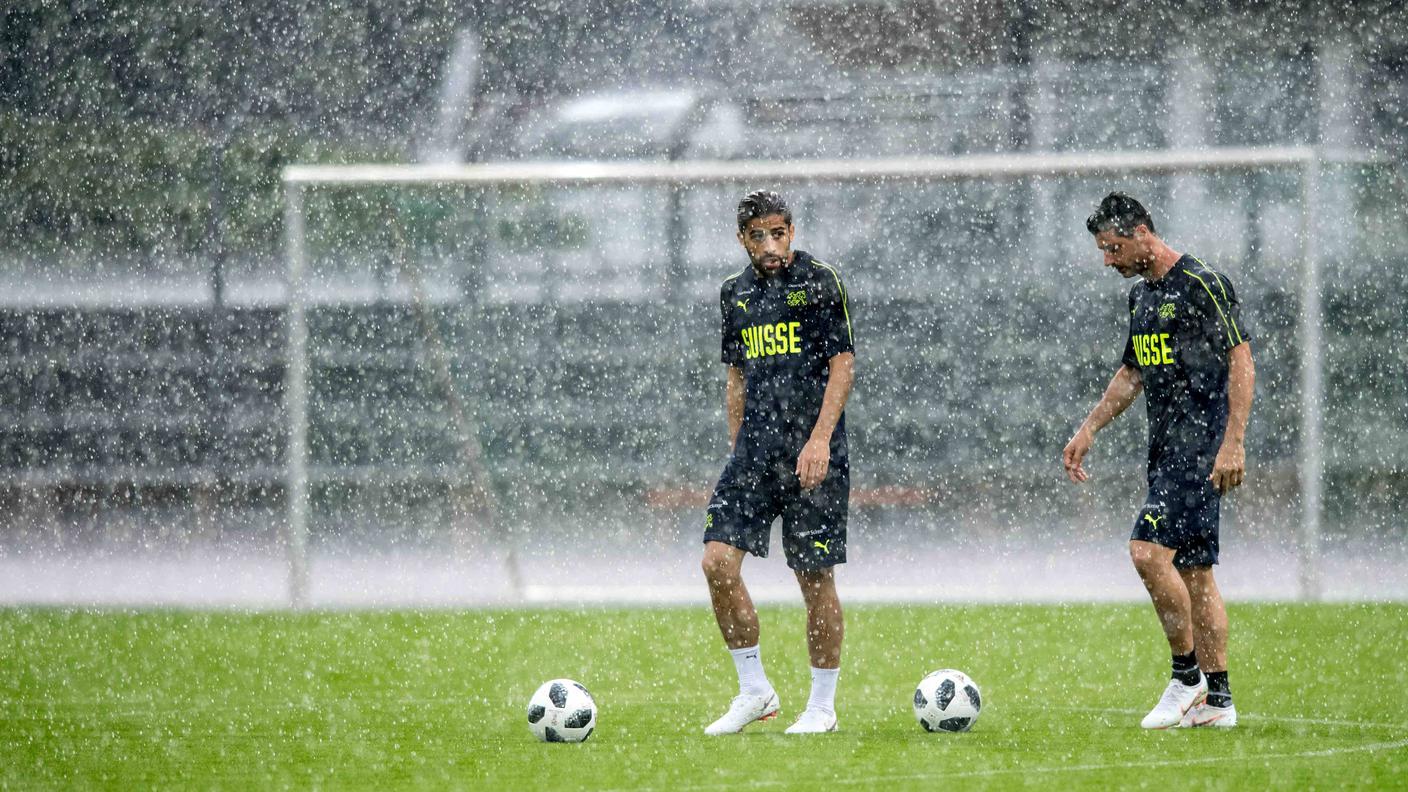 Rodriguez e Dzemaili tentano di allenarsi sotto il diluvio che ha investito Lugano