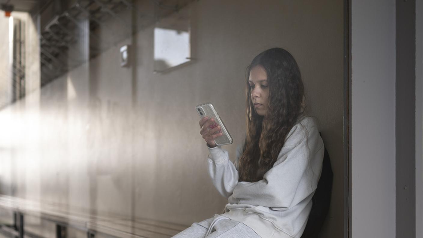 Una studentessa usa lo smartphone durante la ricreazione (foto costruita)