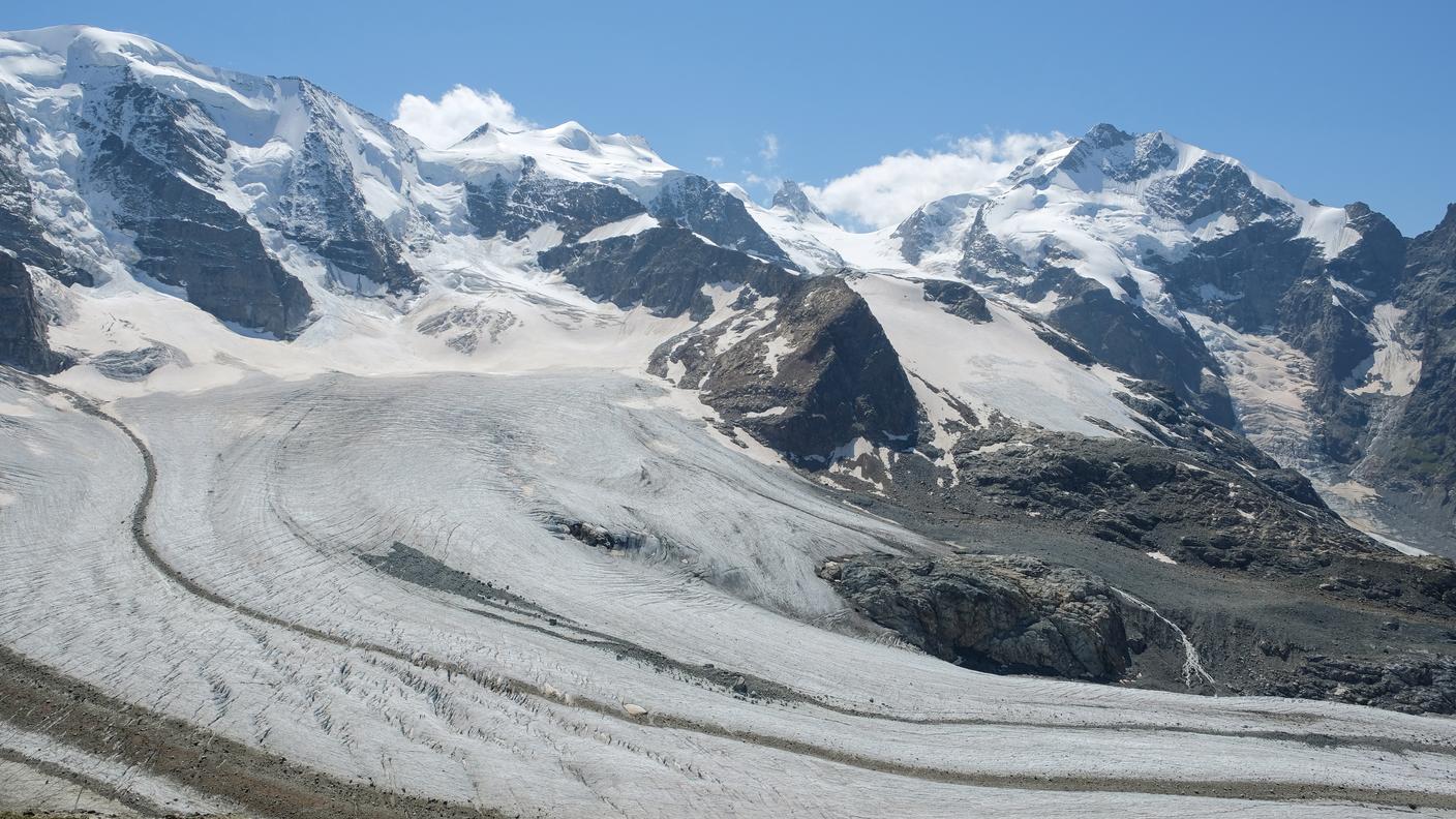 Vista d’alta montagna del ghiacciaio del Pers, con crepacci, rocce affioranti e ghiaccio in progressivo assottigliamento, che evidenzia l’impatto visibile dei cambiamenti climatici sotto le cime innevate del massiccio del Bernina.