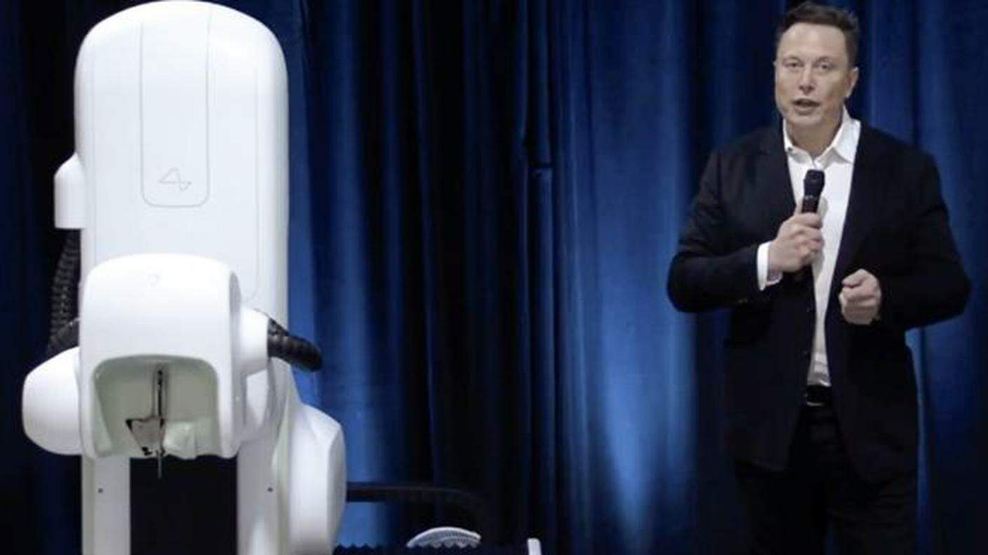 Elon Musk a fianco del robot chirurgico utilizzato per l'impianto