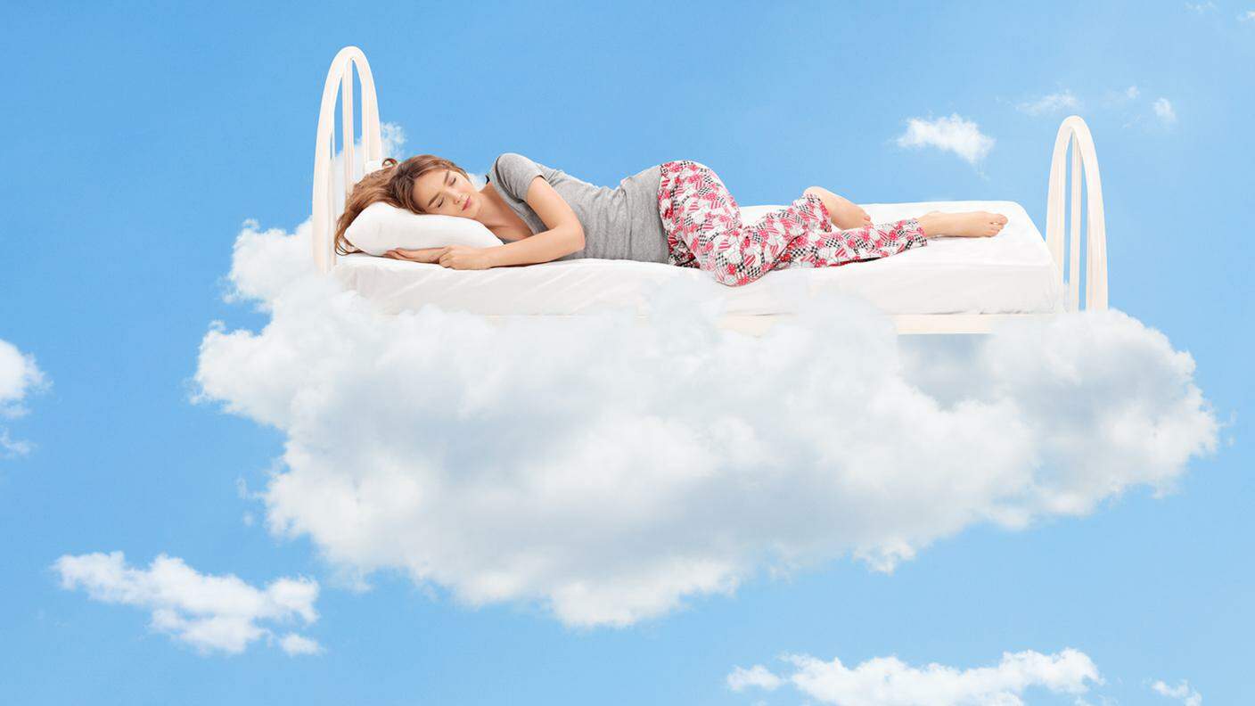 Donna che dorme su un letto comodo tra le nuvole