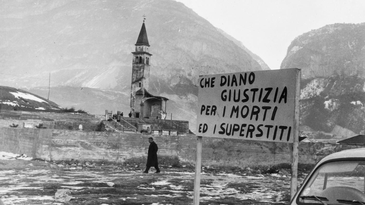 Il campanile della chiesa di Pirago e un cartello che chiede giustizia, vicino a Longarone, Italia