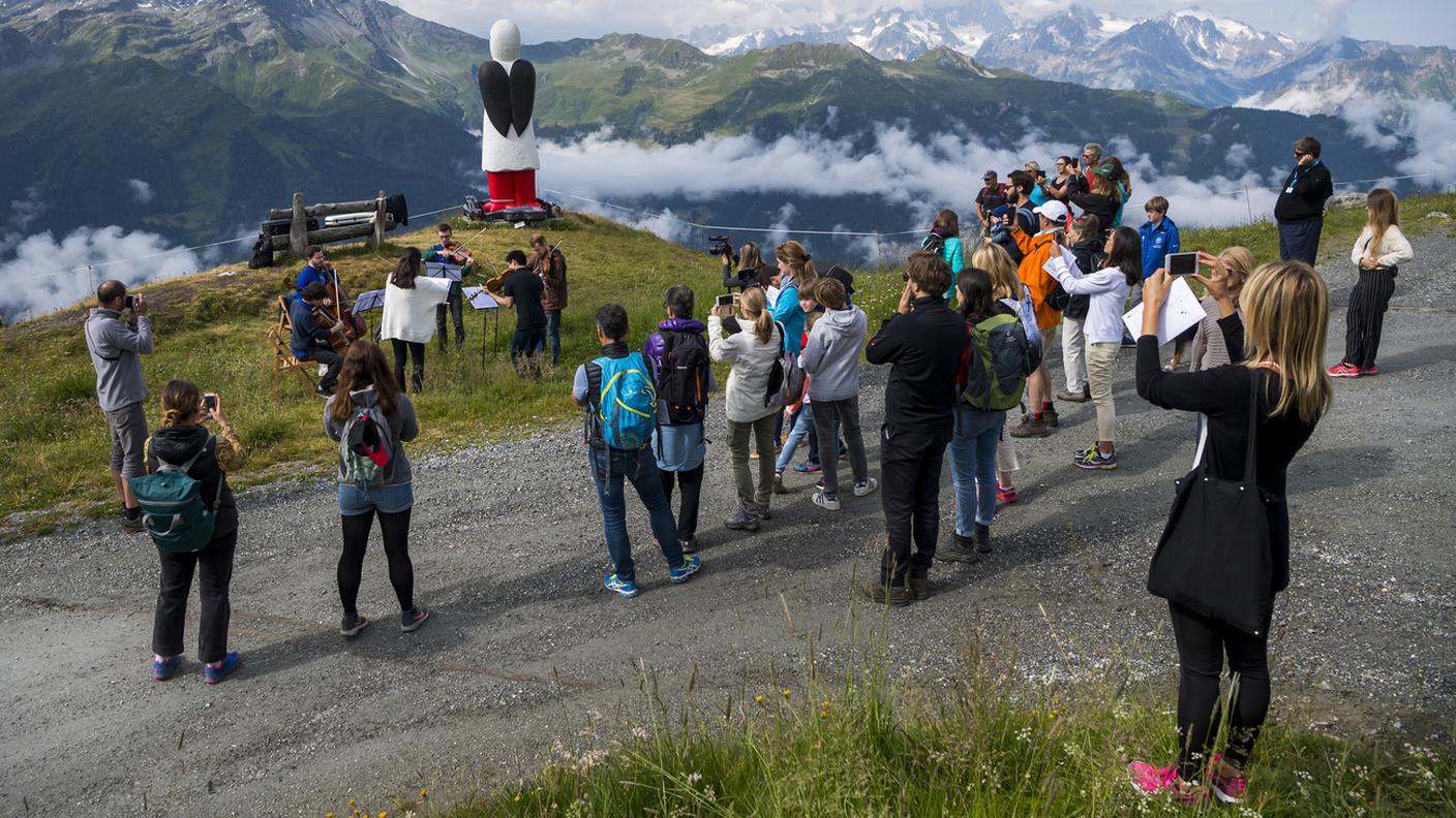 Alcuni musicisti davanti alla scultura "Baby Bringer" dell'artista Donna Dodson a Verbier