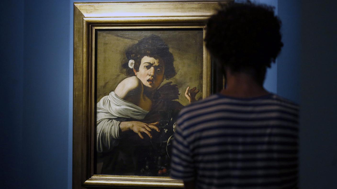 Visitatore di fronte al dipinto "Ragazzo morso da un ramarro", di Caravaggio. Monstra a Roma dalla collezione di Roberto Longhi