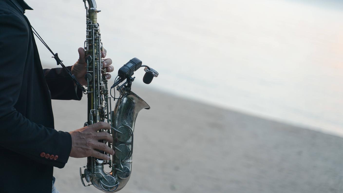 Musician man playing saxophone on the beach
