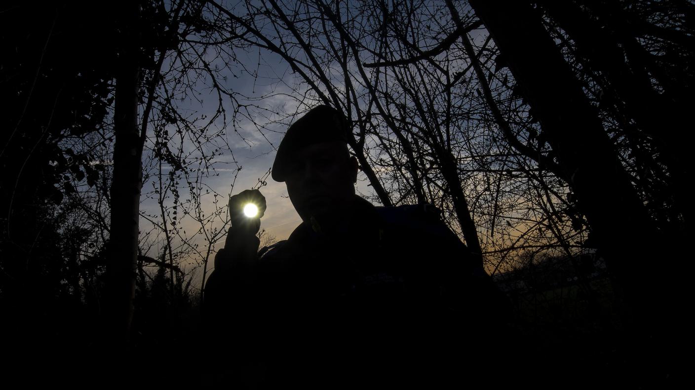 TiPress_Nella foto una guardia di confine mentre controlla il confine Svizzera - Italia all'imbrunire.