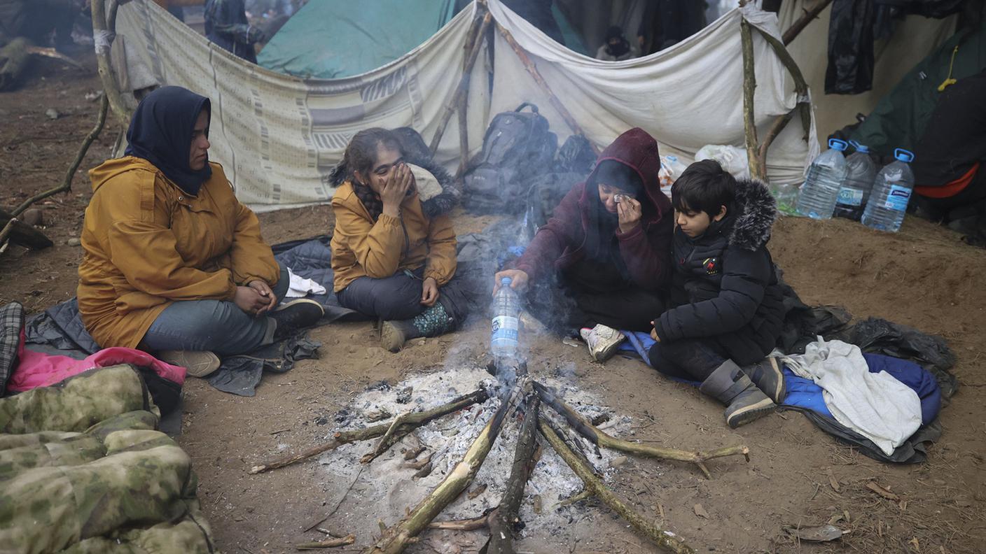 Migranti dal Medio Oriente e da altre parti, si riscaldano al raduno di fuoco al confine tra Bielorussia e Polonia vicino a Grodno, in Bielorussia