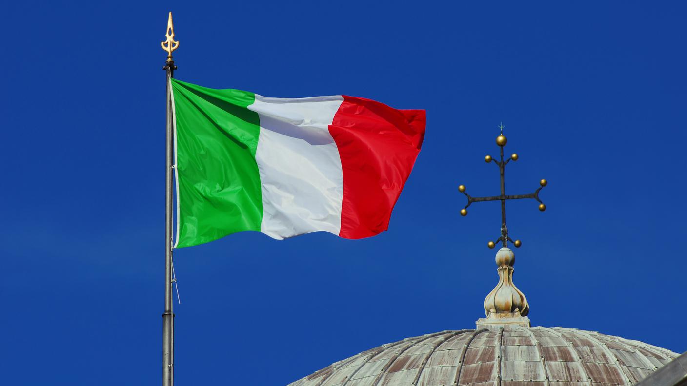 Bandiera Nazionale Italiana sventolante al vento vicino a un croce cristiana