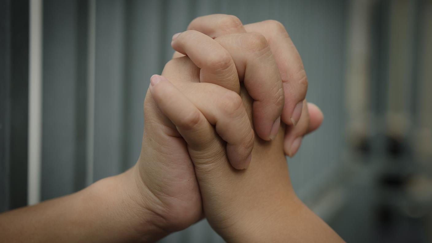 Mamma tiene la mano alla figlia attraverso le sbarre