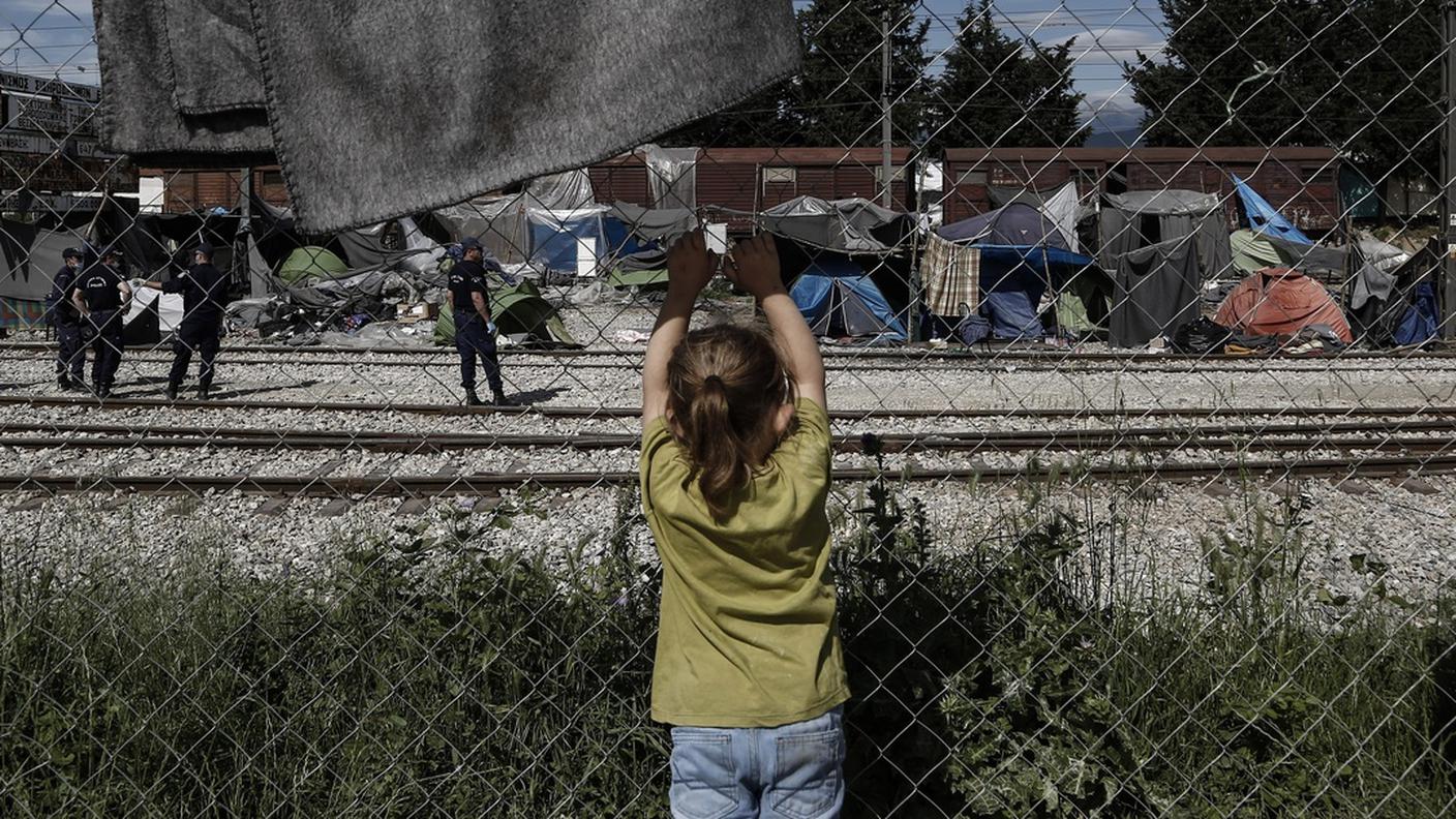 Una ragazza migrante assiste allo sgombero di un campo profughi improvvisato al confine tra Grecia e Macedonia.