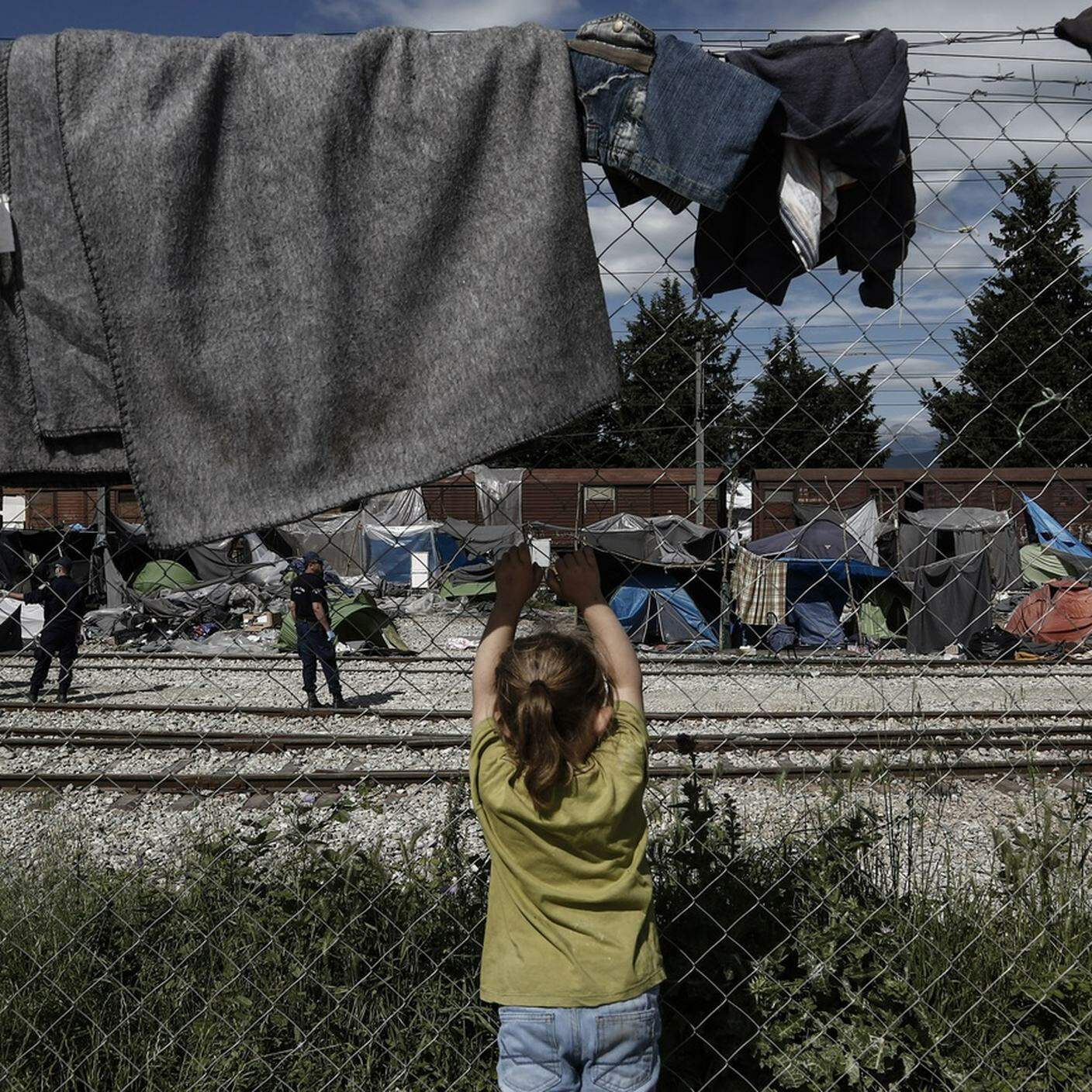 Una ragazza migrante assiste allo sgombero di un campo profughi improvvisato al confine tra Grecia e Macedonia.