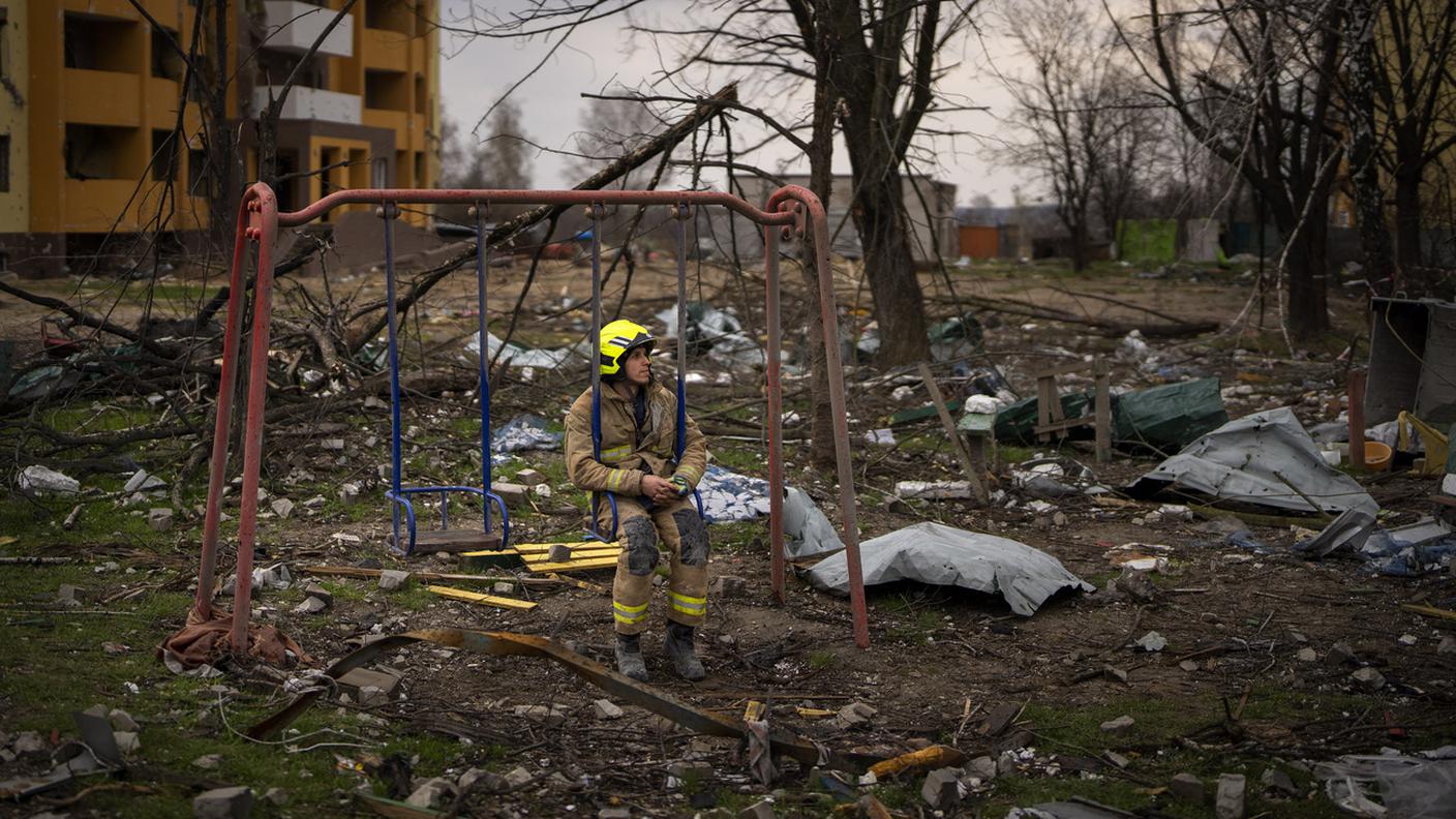 Pompiere seduto su un'altalena vicino a un edificio distrutto, Chernihiv