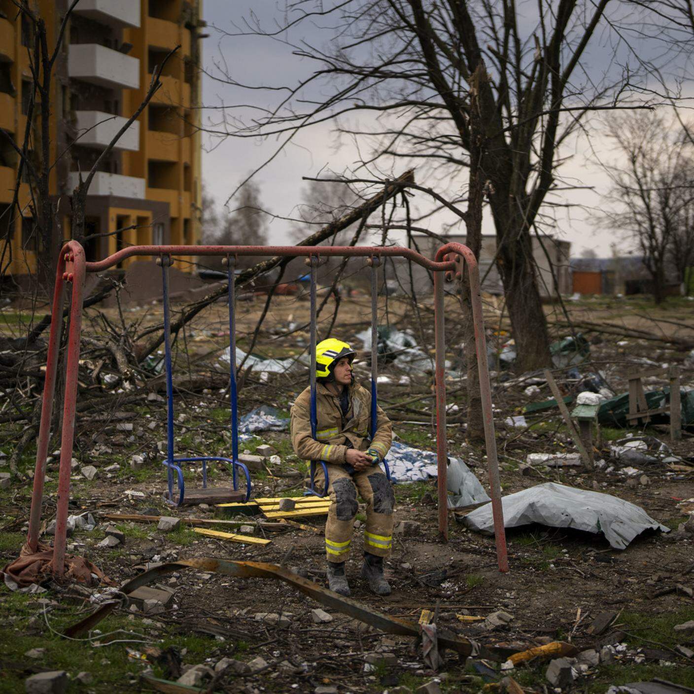 Pompiere seduto su un'altalena vicino a un edificio distrutto, Chernihiv