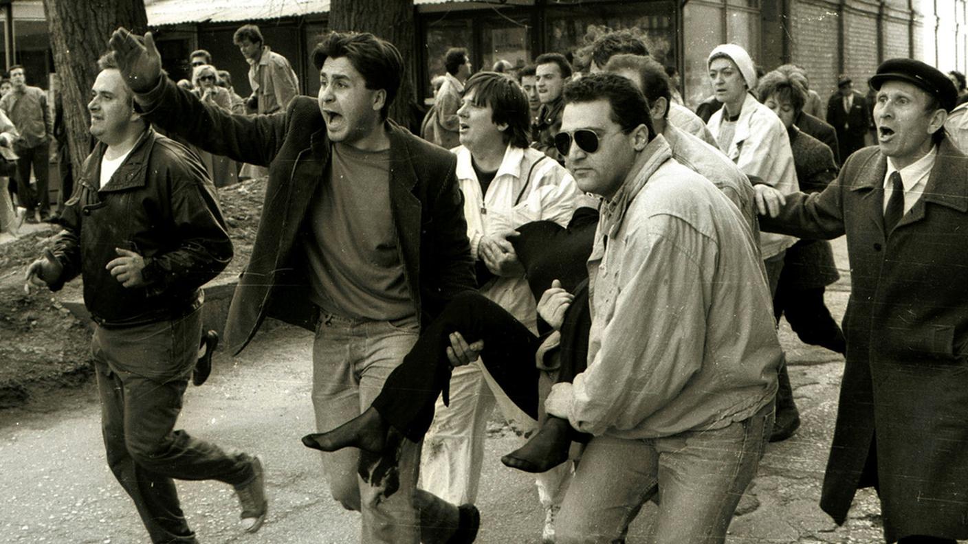 Immagine scattata il 5 aprile 1992 nel centro di Sarajevo che illustra alcuni abitanti che trasportano Olga Sučić, una delle prime vittime della guerra del 1992-1995 (Keystone)