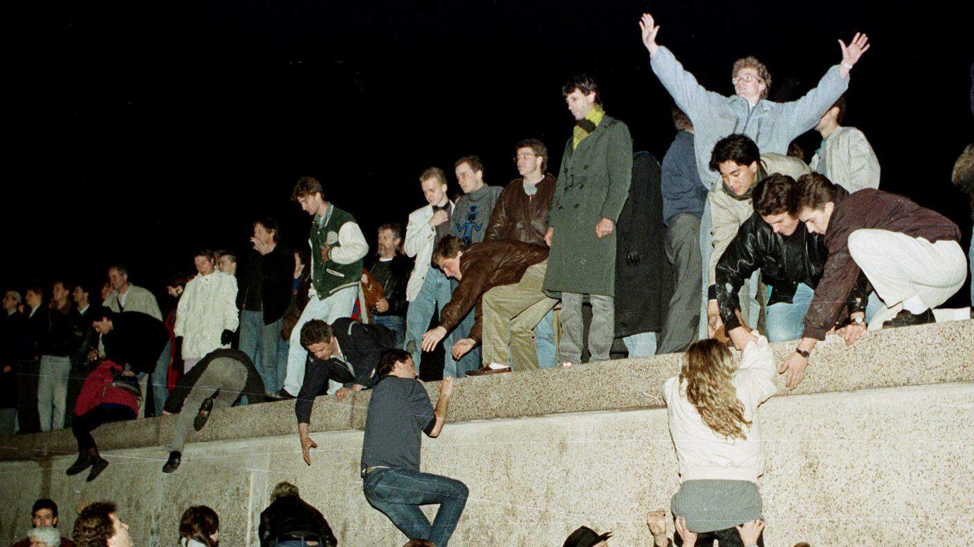 I cittadini della Germania dell'Est scalano il muro di Berlino alla Porta di Brandeburgo, il 10 novembre 1989