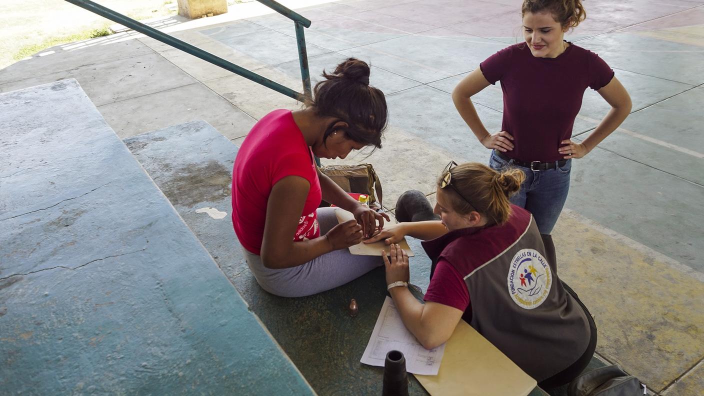 Attività educativa sull'autostima, con l'applicazione di uno smalto con una ragazza in situazione di strada