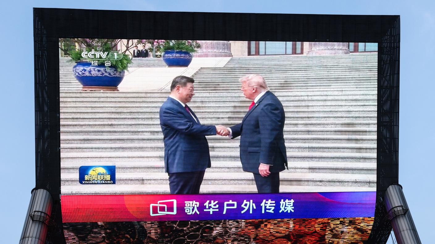 Uno schermo a Pechino mostra la stretta di mano tra Xi Jinping e Donald Trump