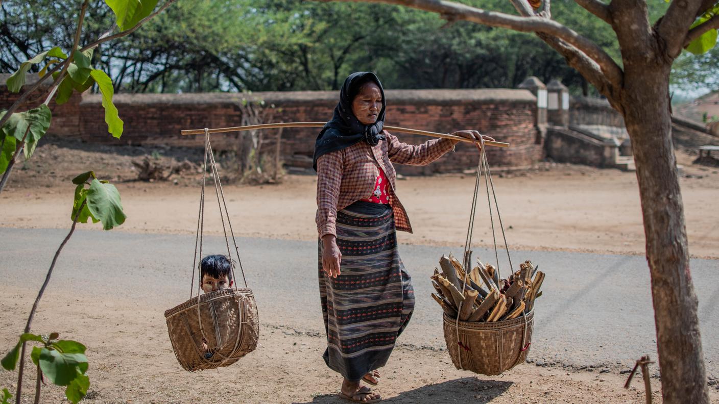 Una donna trasporta legna da ardere e il suo giovane figlio in Myanmar.