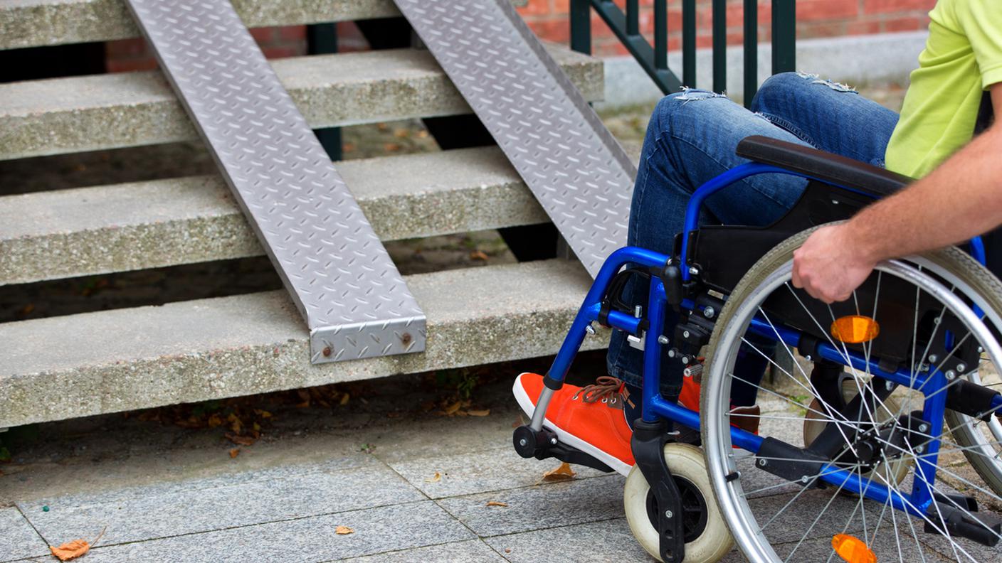 Uomo su sedia a rotelle cerca di salire le scale, handicap, invalidi