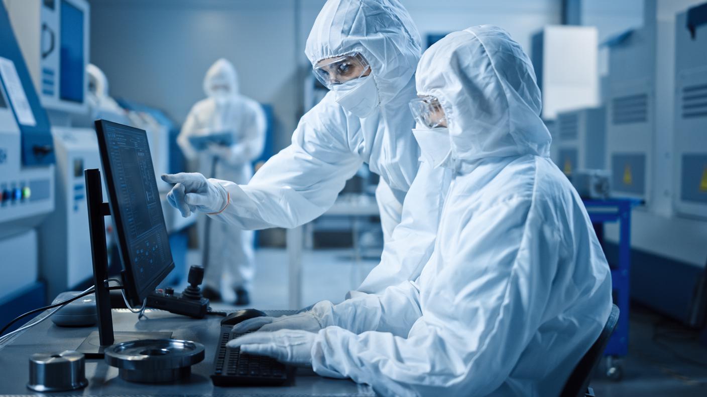 Camera bianca di fabbrica: ingegnere e scienziato che indossa tute e maschere hanno discussione, usano computer che mostra il controllo del sistema infrastrutturale. In background macchinari