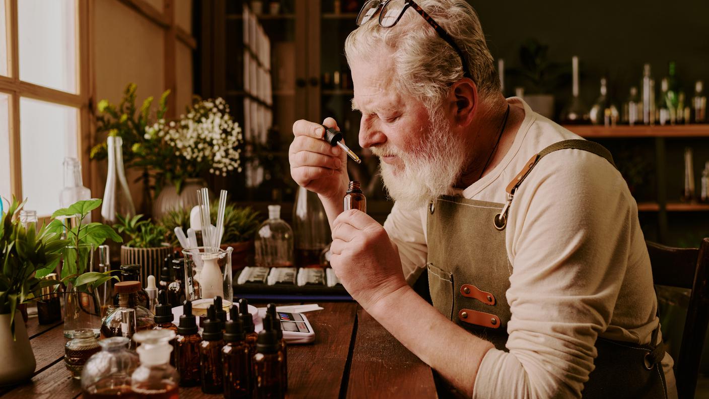 Profumiere maschio seduto a tavola, creazione di aroma, profumo artigianale