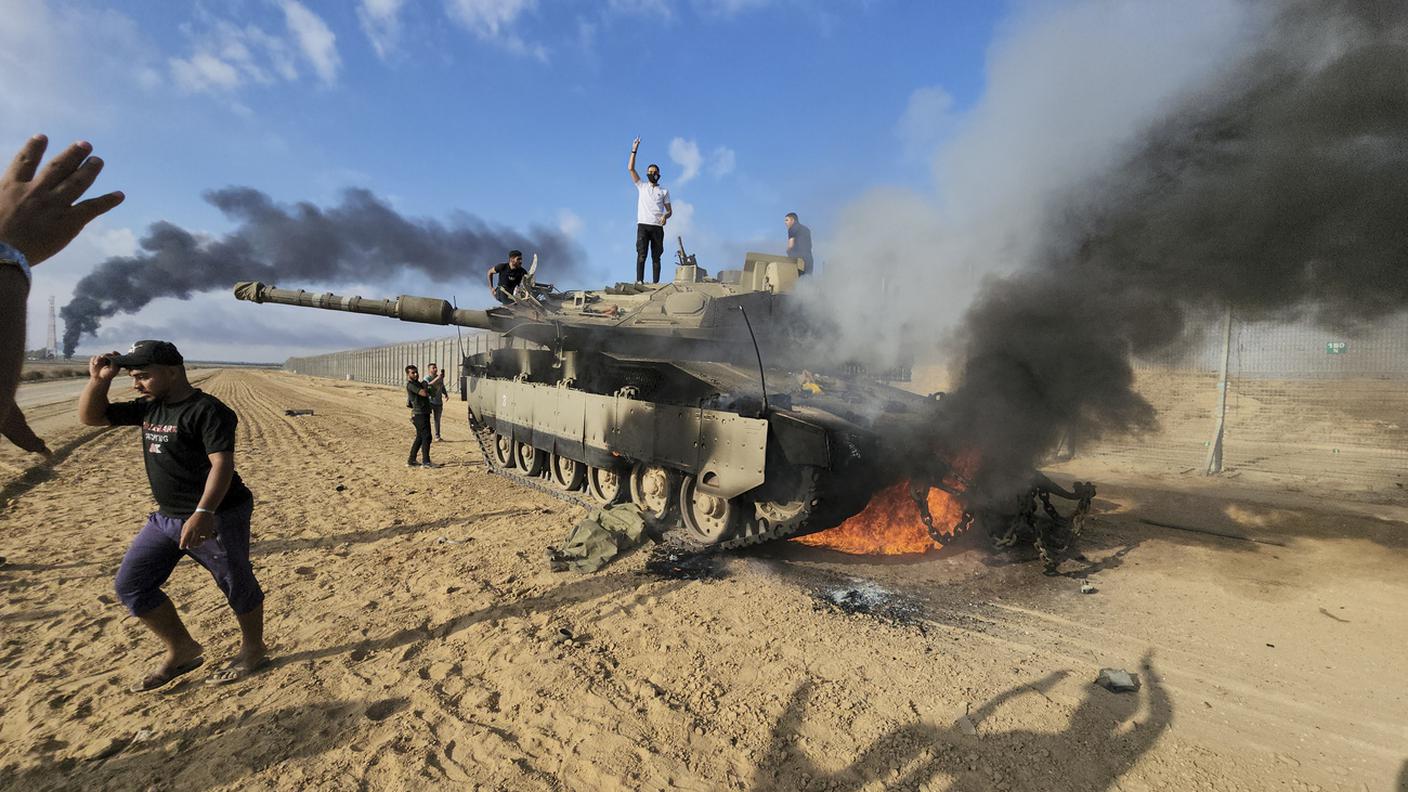 Palestinesi accanto a un carro armato israeliano distrutto sulla Striscia di Gaza a est di Khan Younis.