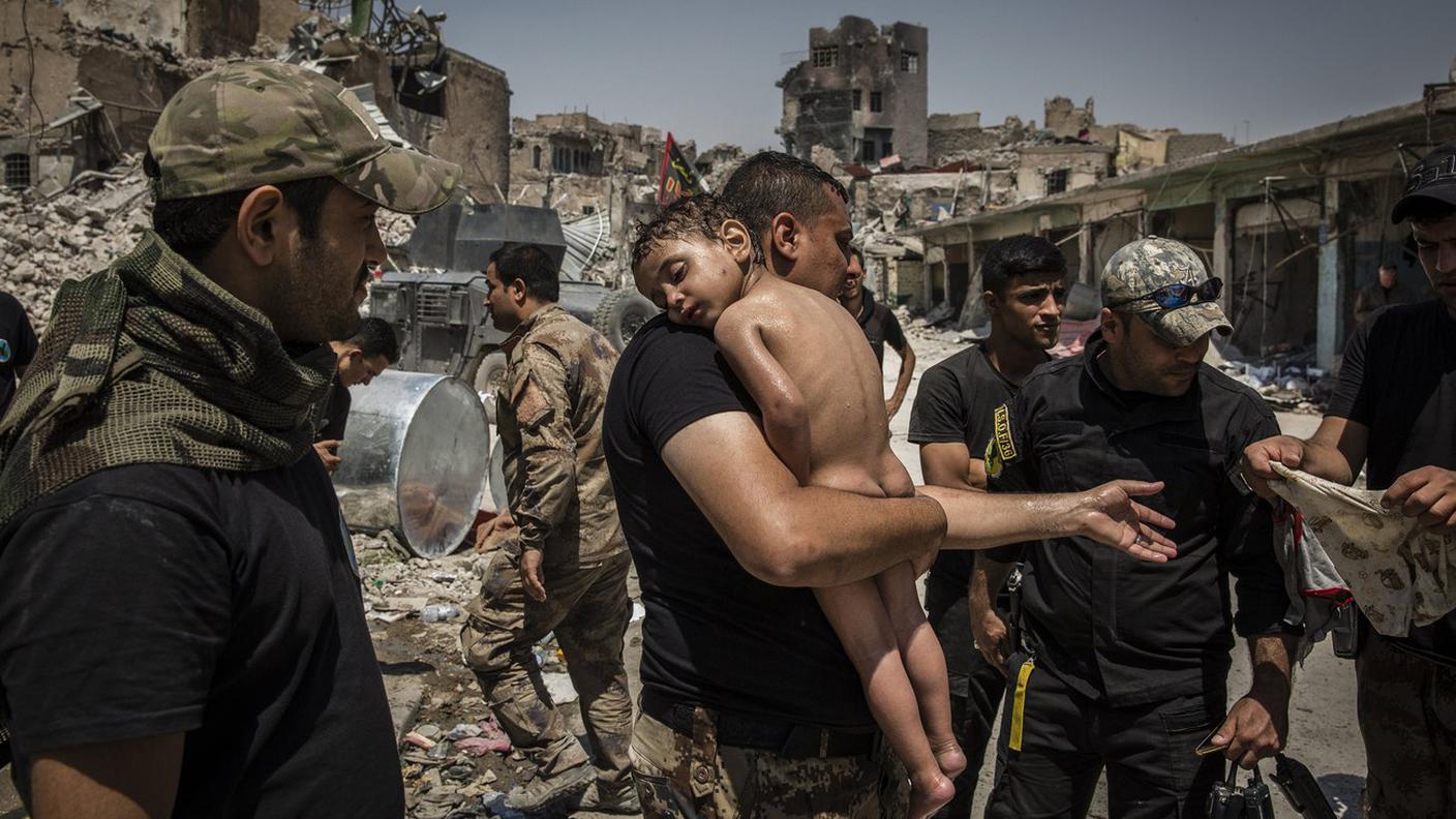 Un bambino nudo in braccio a un soldato delle forze speciali irachene a Mosul, foto di Ivor Prickett (Panos Pictures, per il New York Times)