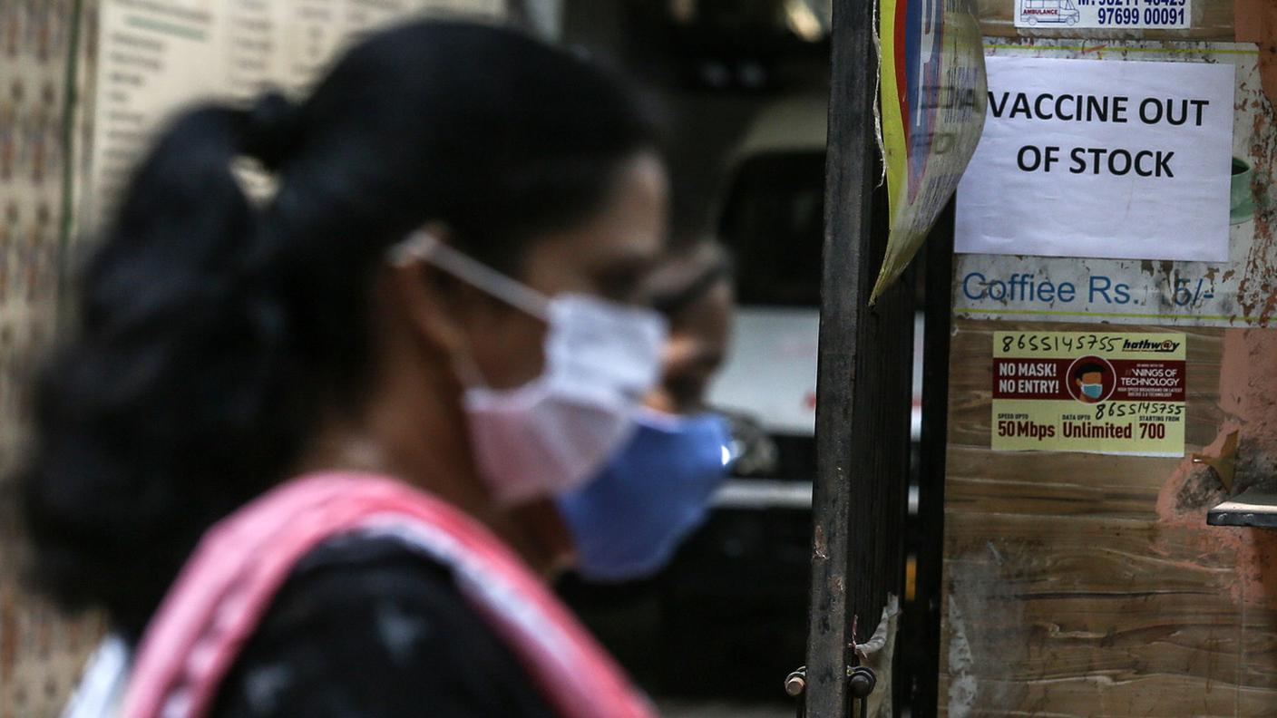 Persone che indossano maschere passano davanti a un avviso sulla carenza di vaccino contro il coronavirus COVID-19 fuori da un centro di vaccinazione a Mumbai, India, 9 aprile 2021