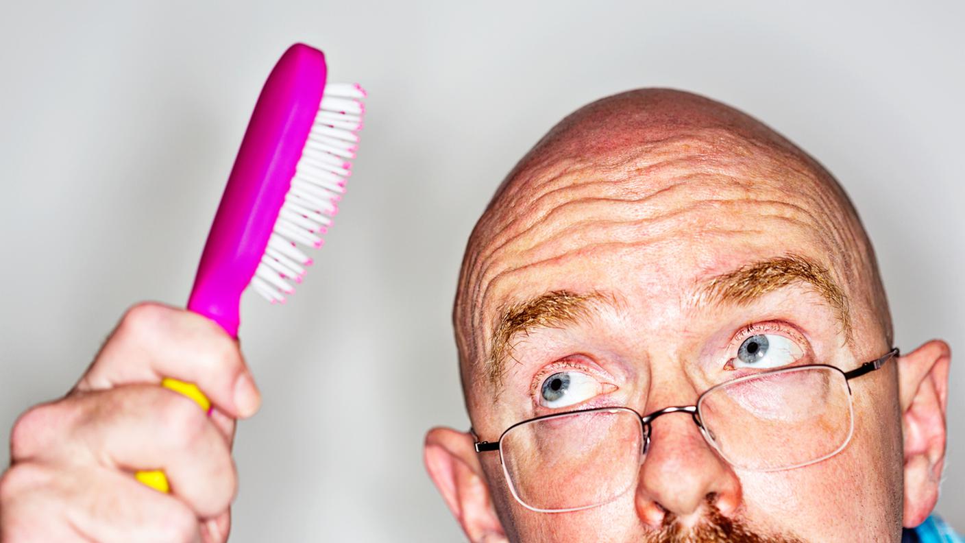 Uomo calvo tentativi di spazzola i suoi capelli inesistente