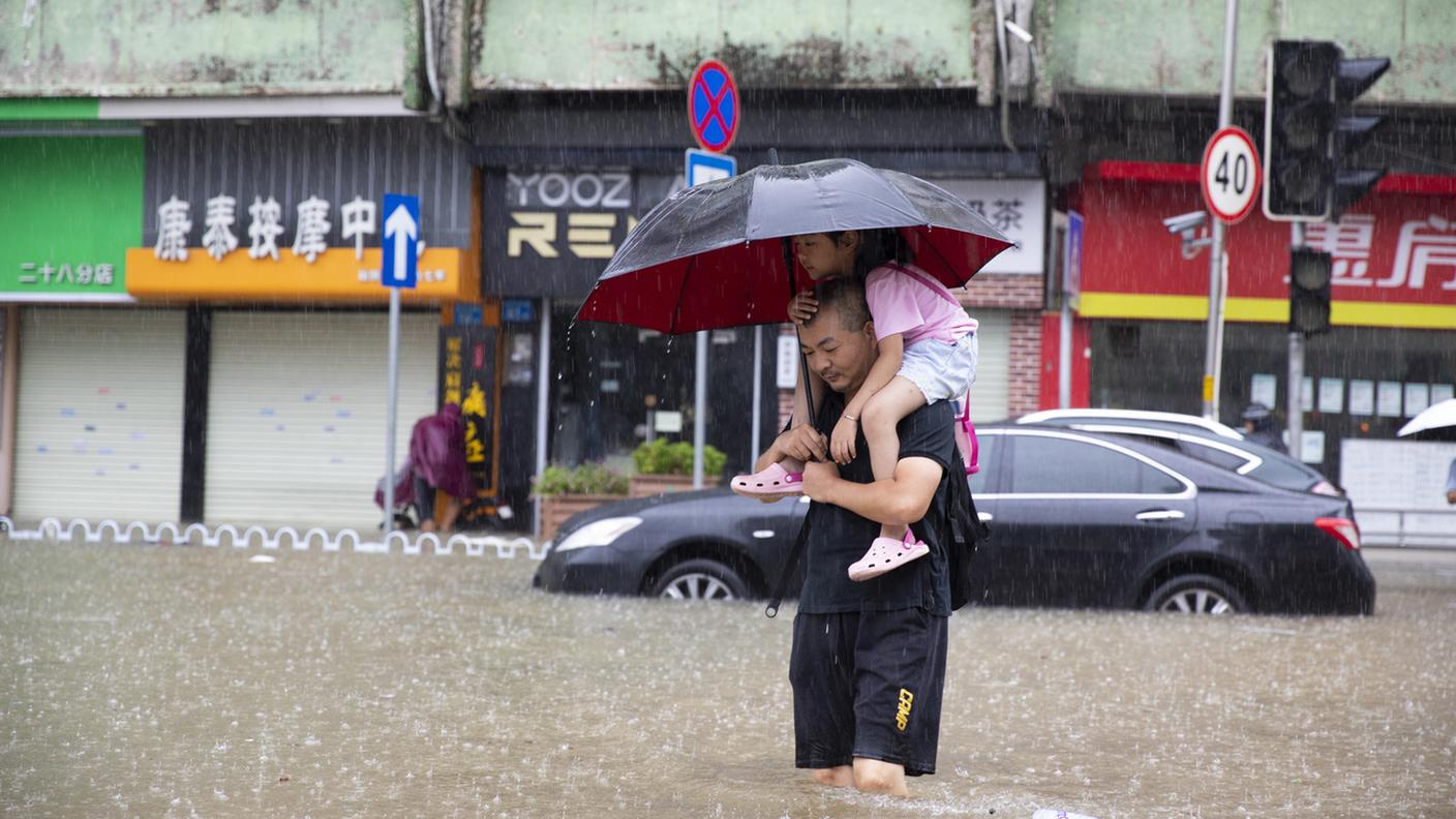 Uomo porta in spalle la figlia durante l'alluvione in Cina 